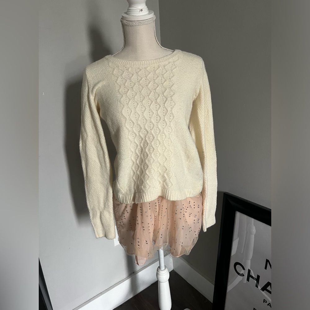 Cream Anthropologie sweater with pink underlay.